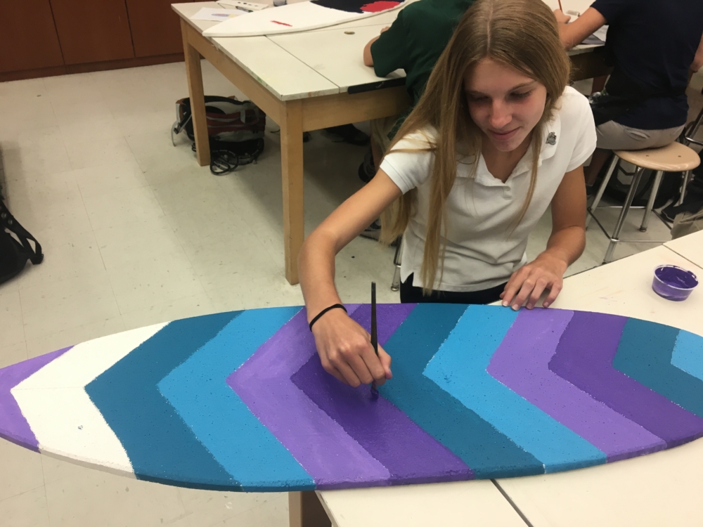 One of Mrs. Theoharris students working on a surfboard for an art project in which she hopes student will be able to be creative while not feeling  limited . (via, Jessica Gross, freshman)