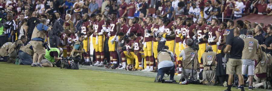 Some members of the Washington Redskins kneel before a game with the Oakland Raiders in September, 2017. (via Keith Allison  [CC BY-SA 2.0])