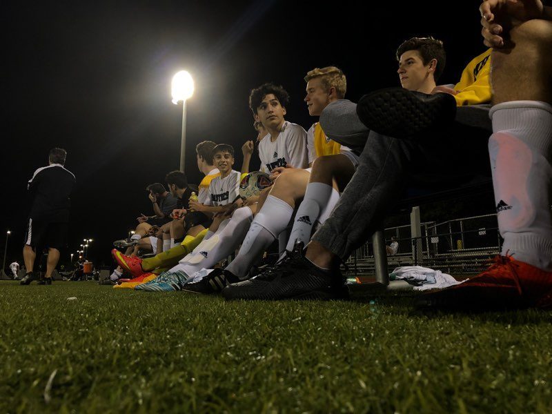 PC boys soccer players wait on the sidelines, getting ready for a big game.  