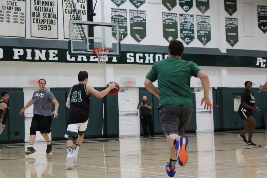 Senior Brian Anderson runs towards the hoop with the basketball as Mr. Mark Spitzig follows. 