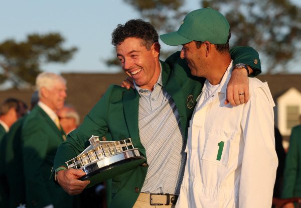 Golf - The Masters - Augusta National Golf Club, Augusta, Georgia, U.S. - April 12, 2026 Northern Ireland's Rory McIlroy with his caddie Harry Diamond as he celebrates with his green jacket and the trophy after winning The Masters REUTERS/Mike Segar